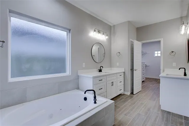 a spacious bathroom with a tub sink and mirror