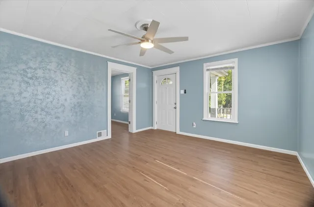 a view of an empty room with wooden floor and a window