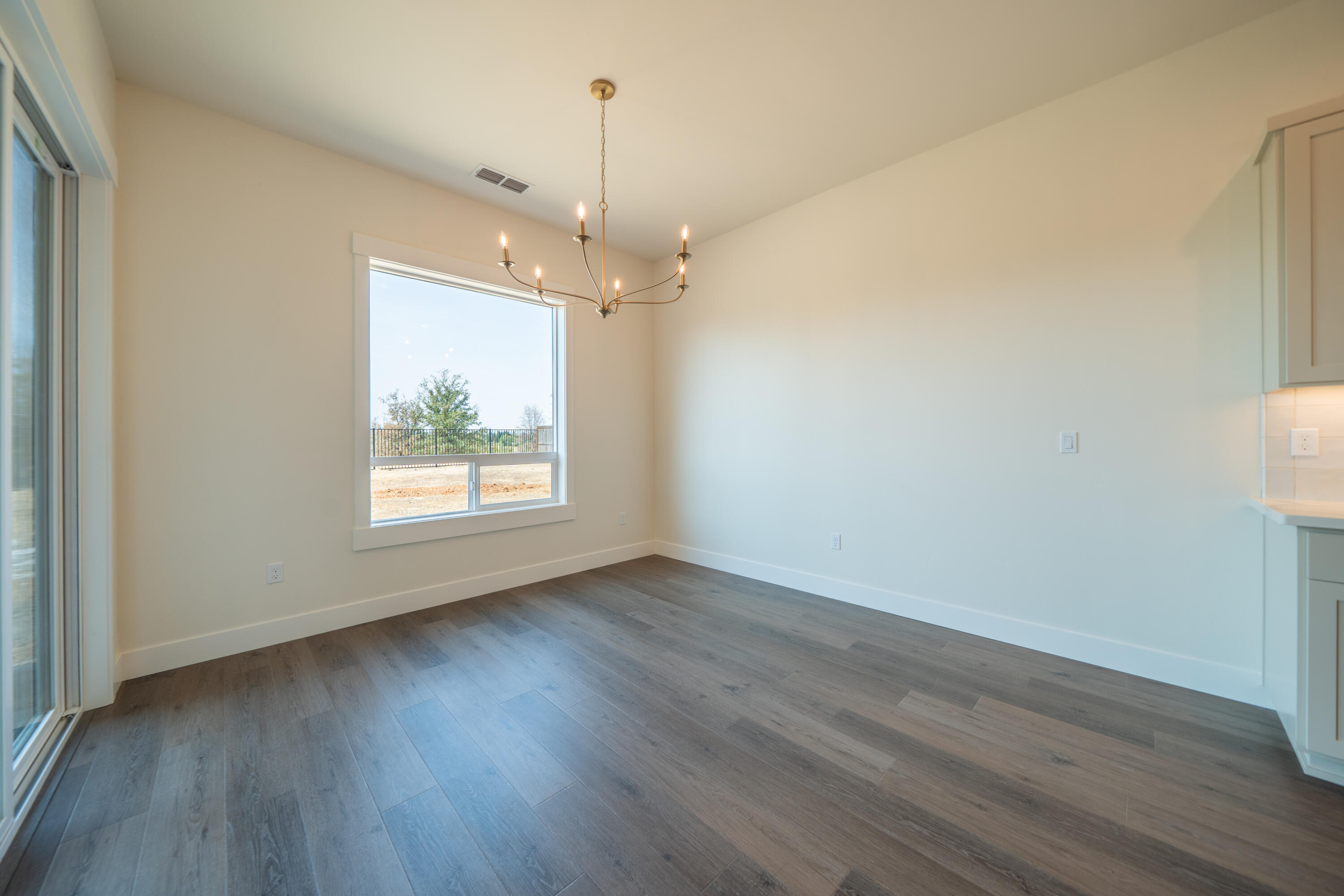 3792 Thomason Trail Redding, CA 96002 - Photo 11 of 42 an empty room with wooden floor and windows