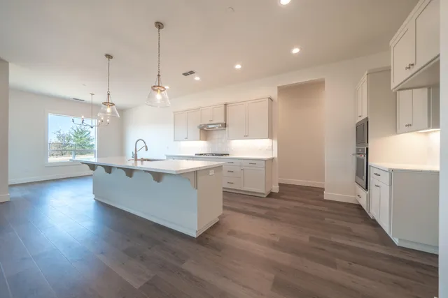 a large kitchen with cabinets wooden floor and stainless steel appliances