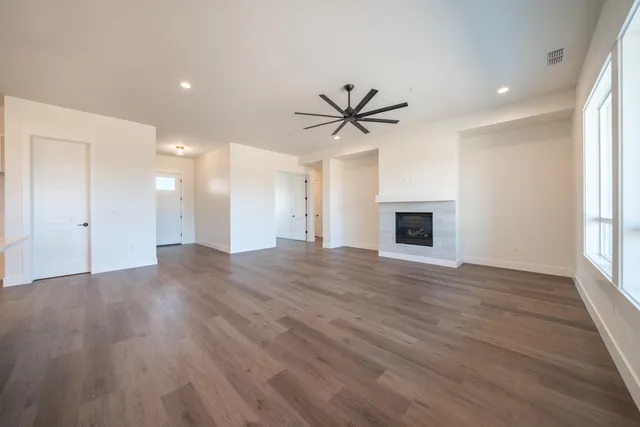 a view of an empty room with a window and wooden floor