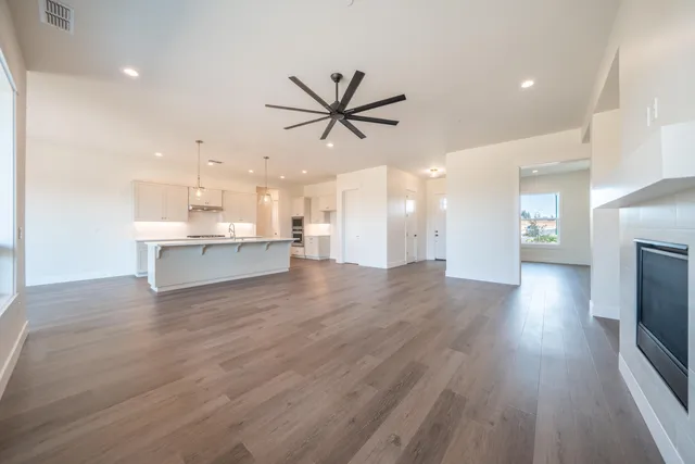 a view of an empty room with wooden floor and a fireplace