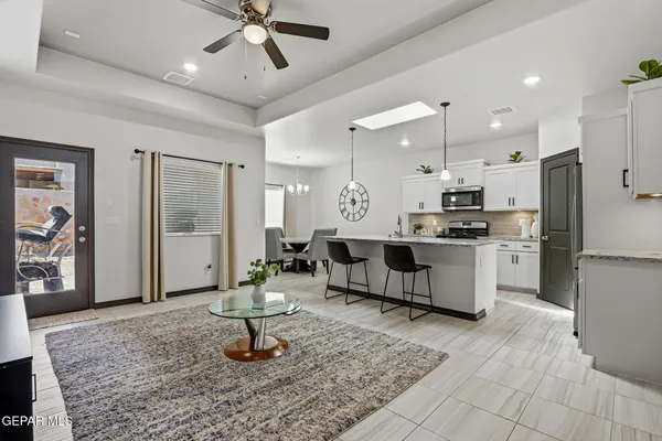 a kitchen with stainless steel appliances kitchen island granite countertop a refrigerator a stove a sink a dining table and chairs with wooden floor
