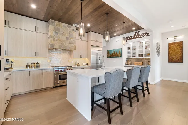 a kitchen with stainless steel appliances kitchen island granite countertop a table chairs sink and white cabinets