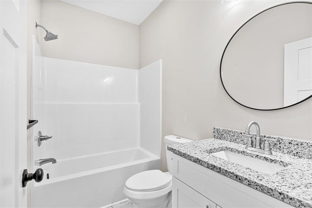 152 Washington Street Dalton, GA 30721 - Photo 32 of 40 a bathroom with a granite countertop sink a toilet and a mirror