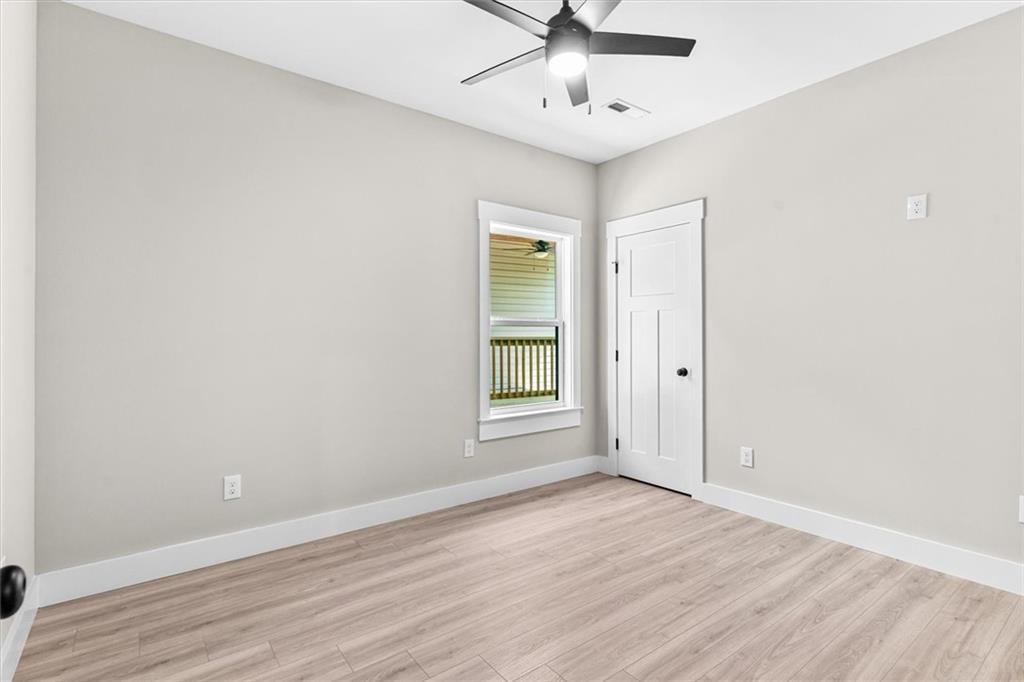 152 Washington Street Dalton, GA 30721 - Photo 34 of 40 an empty room with wooden floor ceiling fan and windows
