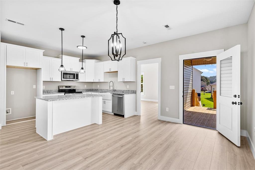 152 Washington Street Dalton, GA 30721 - Photo 37 of 40 a kitchen with stainless steel appliances kitchen island a refrigerator a stove a microwave and a wooden floor