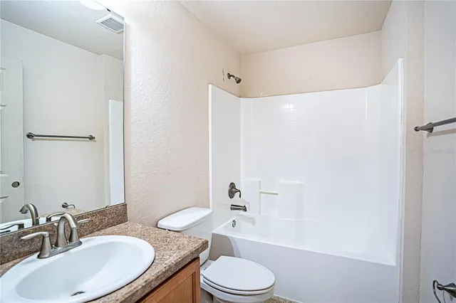 a bathroom with a granite countertop sink toilet a mirror and shower