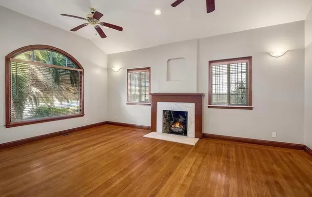 a view of empty room with wooden floor and fan