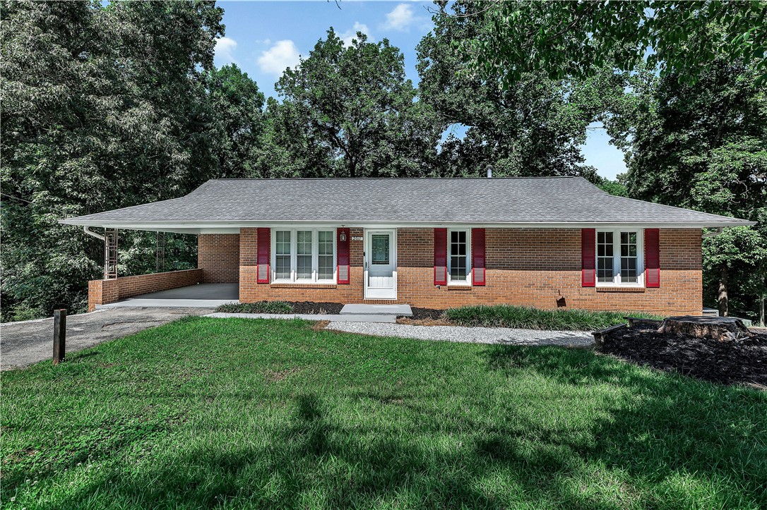 2011 Forest Drive Seneca, SC 29672 - Photo 1 of 36 Brick ranch home featuring an attached carport and a welcoming front walkway, nestled among mature trees.