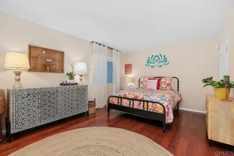 a bedroom with a bed and a dresser with wooden floor