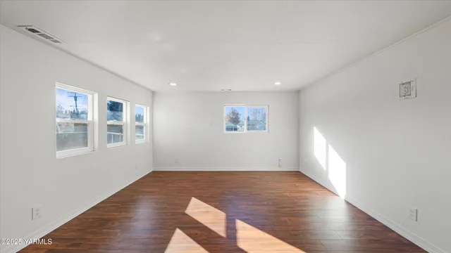 an empty room with wooden floor and windows