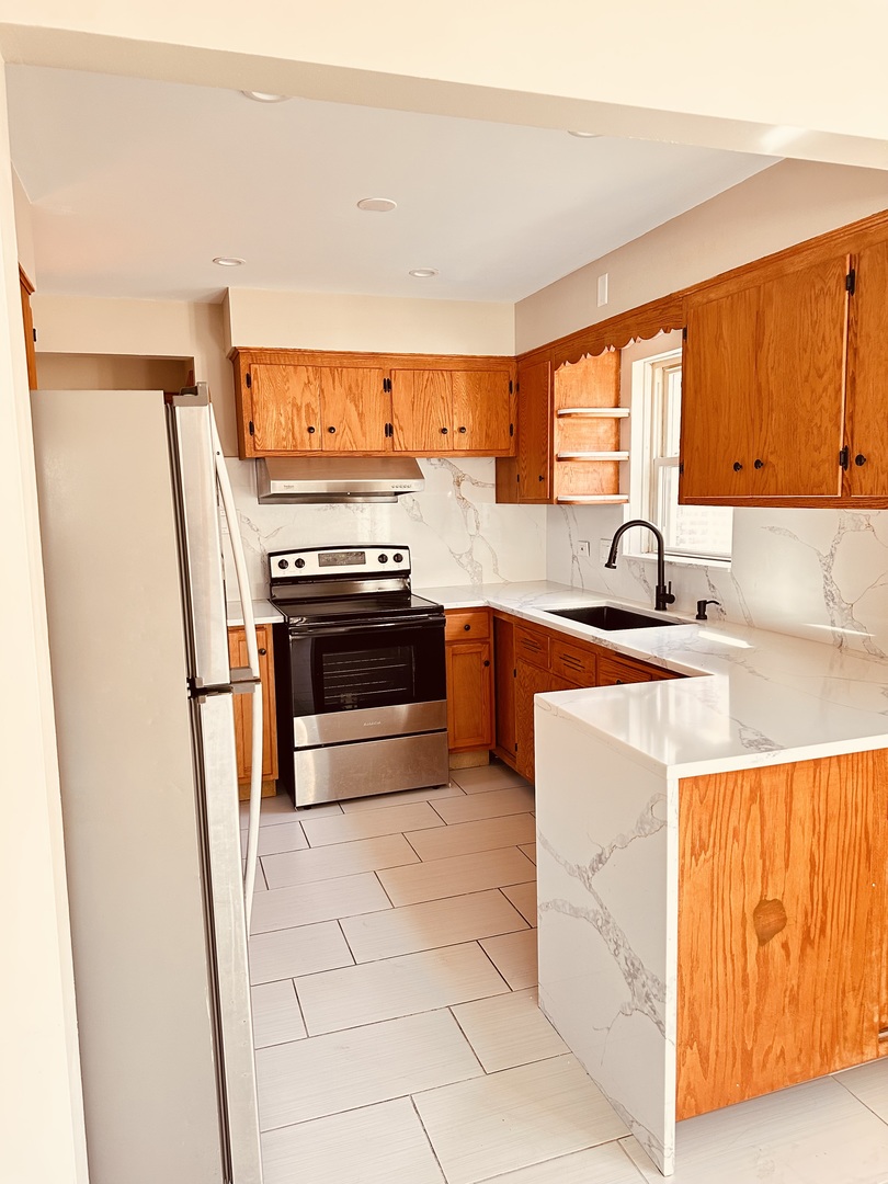 2823 West 71st Street Chicago, IL 60629 - Photo 6 of 18 a kitchen with stainless steel appliances granite countertop a sink and a stove