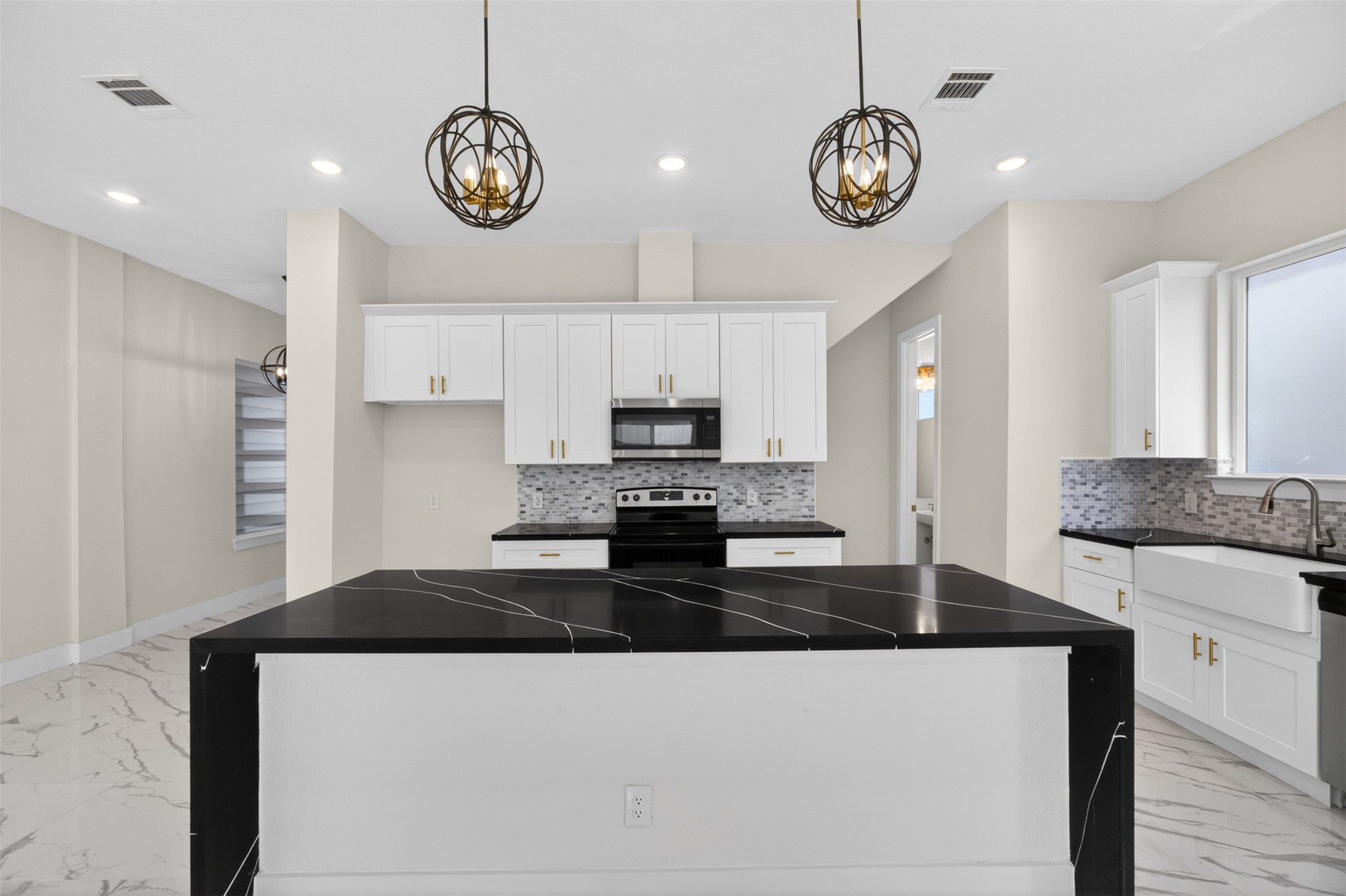 5906 St Augustine Street, Unit F Houston, TX 77021 - Photo 6 of 34 Front-facing kitchen view showcasing the oversized island, white cabinetry, and coordinating black countertops.