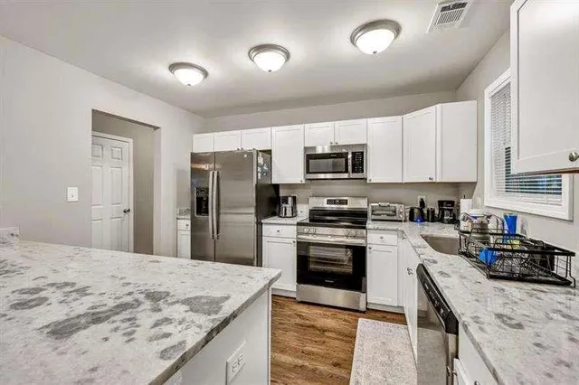 a kitchen with stainless steel appliances granite countertop a sink stove refrigerator and cabinets
