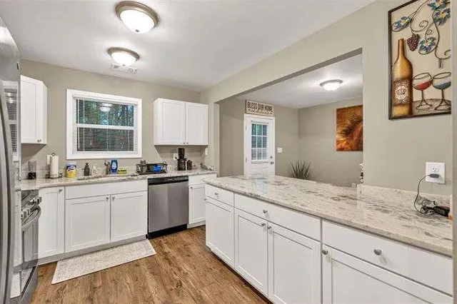 a kitchen with granite countertop cabinets stainless steel appliances a sink and a window