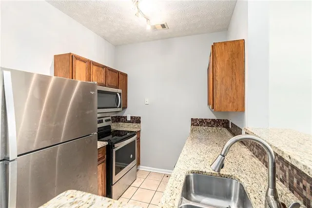 a kitchen with stainless steel appliances granite countertop a refrigerator sink and stove