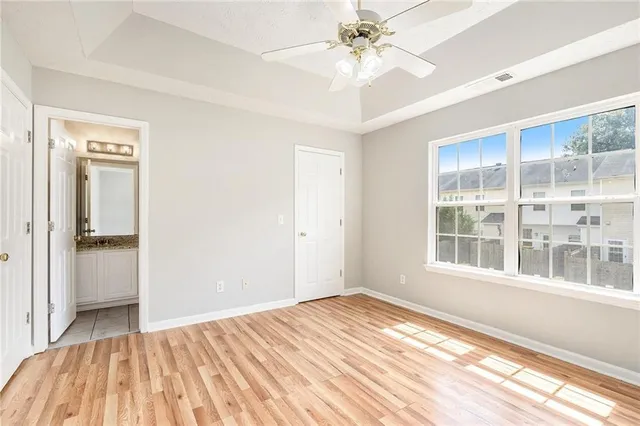 a view of empty room with wooden floor and fan