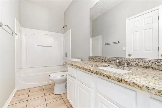 a bathroom with a granite countertop sink a toilet and a shower