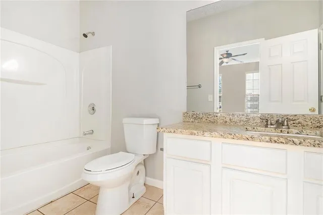 a bathroom with a granite countertop sink toilet mirror vanity and bathtub