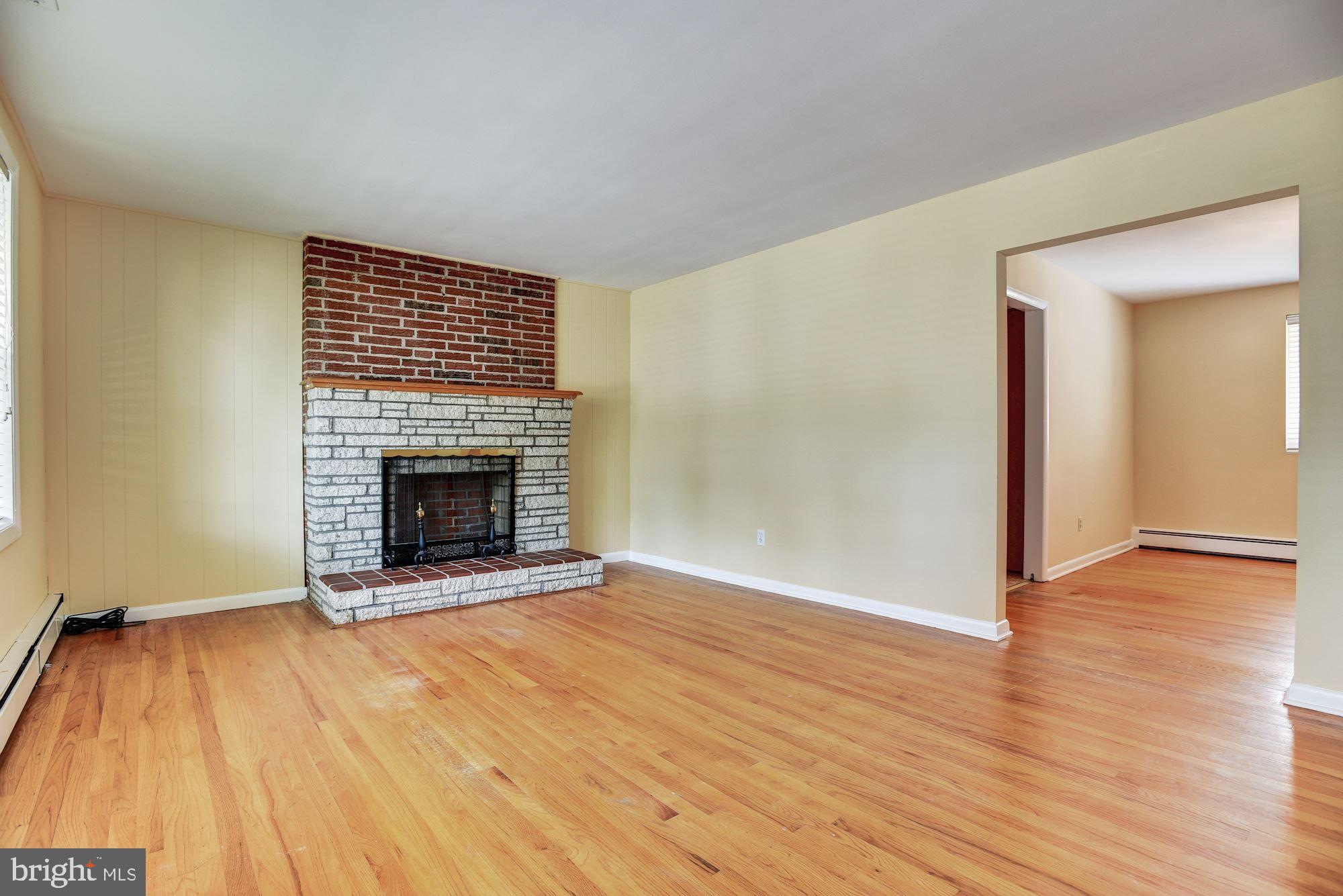 8492 Laurel Road Pasadena, MD 21122 - Photo 5 of 46 a view of an empty room with wooden floor a fireplace and a window