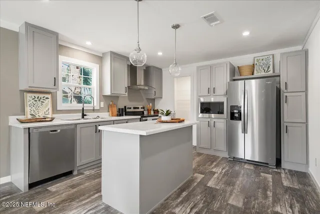 a kitchen with stainless steel appliances granite countertop a refrigerator a sink dishwasher a stove and white cabinets with wooden floor