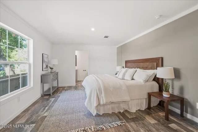 a bedroom with a large bed a chandelier and windows