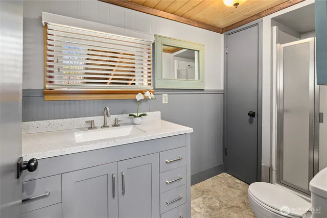 a bathroom with a granite countertop sink toilet a mirror and shower