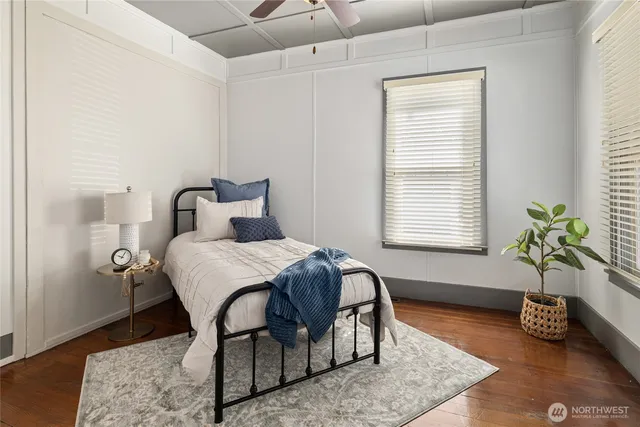 a bedroom with a bed table chair and wooden floor