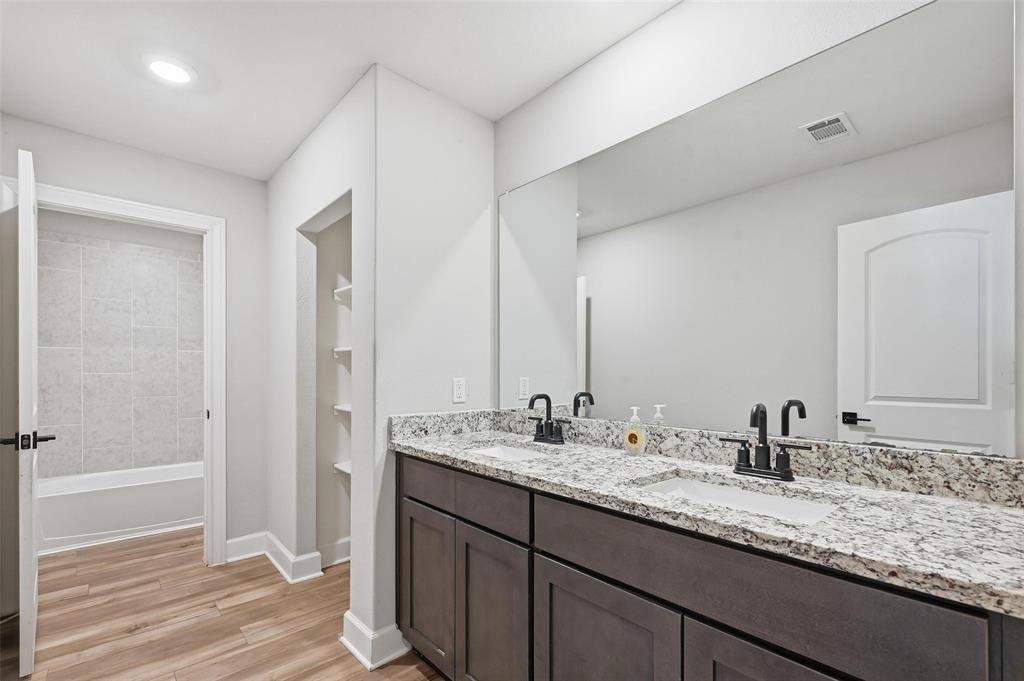 7612 Duck Bay Road Fort Worth, TX 76120 - Photo 18 of 32 a bathroom with a sink double vanity granite tub shower and a mirror