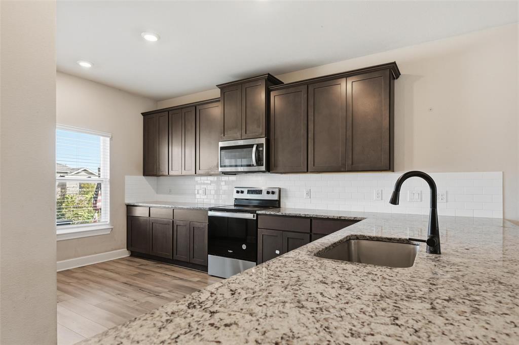 7612 Duck Bay Road Fort Worth, TX 76120 - Photo 4 of 32 a kitchen with stainless steel appliances granite countertop a stove a sink and a microwave