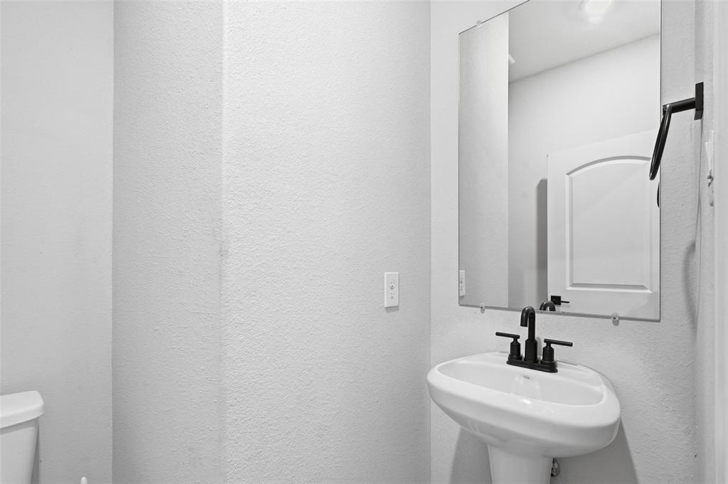 7612 Duck Bay Road Fort Worth, TX 76120 - Photo 8 of 32 a bathroom with a sink a toilet and mirror