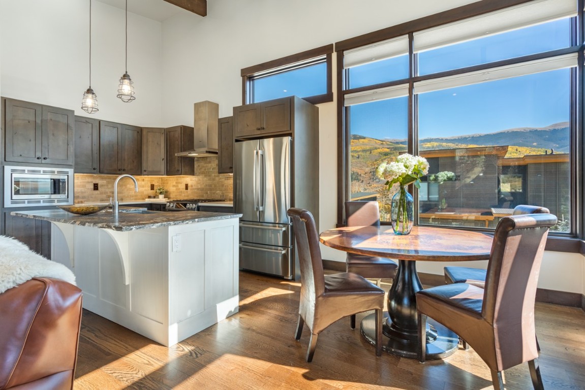 151 Moss Way Silverthorne, CO 80498 - Photo 8 of 31 a kitchen with stainless steel appliances kitchen island granite countertop a refrigerator a stove a dining table and chairs with wooden floor