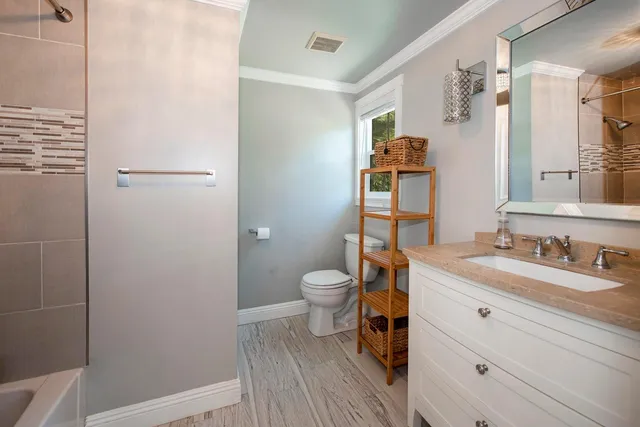 a bathroom with a granite countertop toilet a sink and a mirror