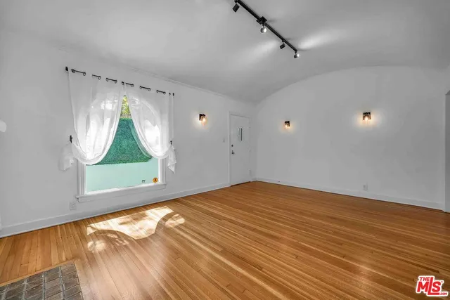 a view of empty room with wooden floor and fan