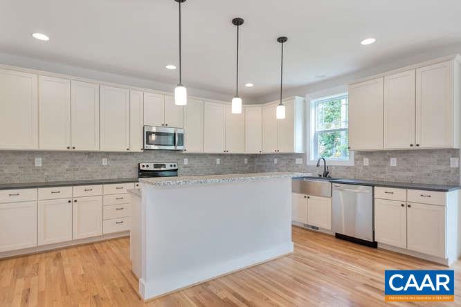 128 Wexford Ridge Road Ruckersville, VA 22968 - Photo 12 of 19 a kitchen with kitchen island granite countertop wooden floors white cabinets and white appliances