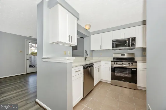 a kitchen with cabinets stainless steel appliances and wooden floor