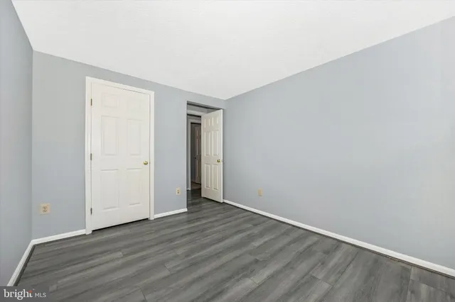 a view of an empty room with wooden floor and closet