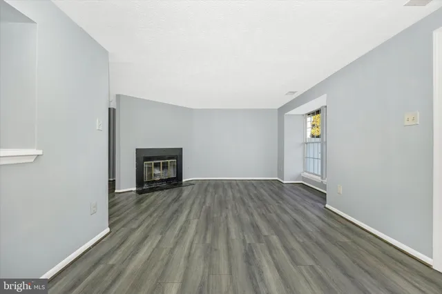 an empty room with wooden floor and fireplace