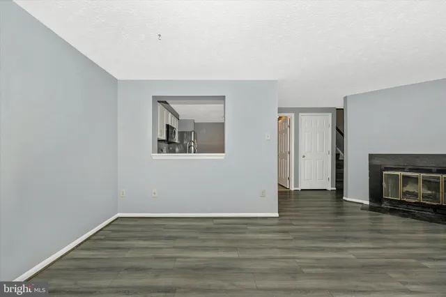 a view of an empty room with wooden floor fireplace and a window