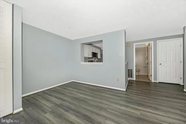 a view of an empty room with wooden floor and closet