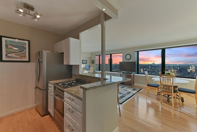 a living room with stainless steel appliances furniture a rug and a large window