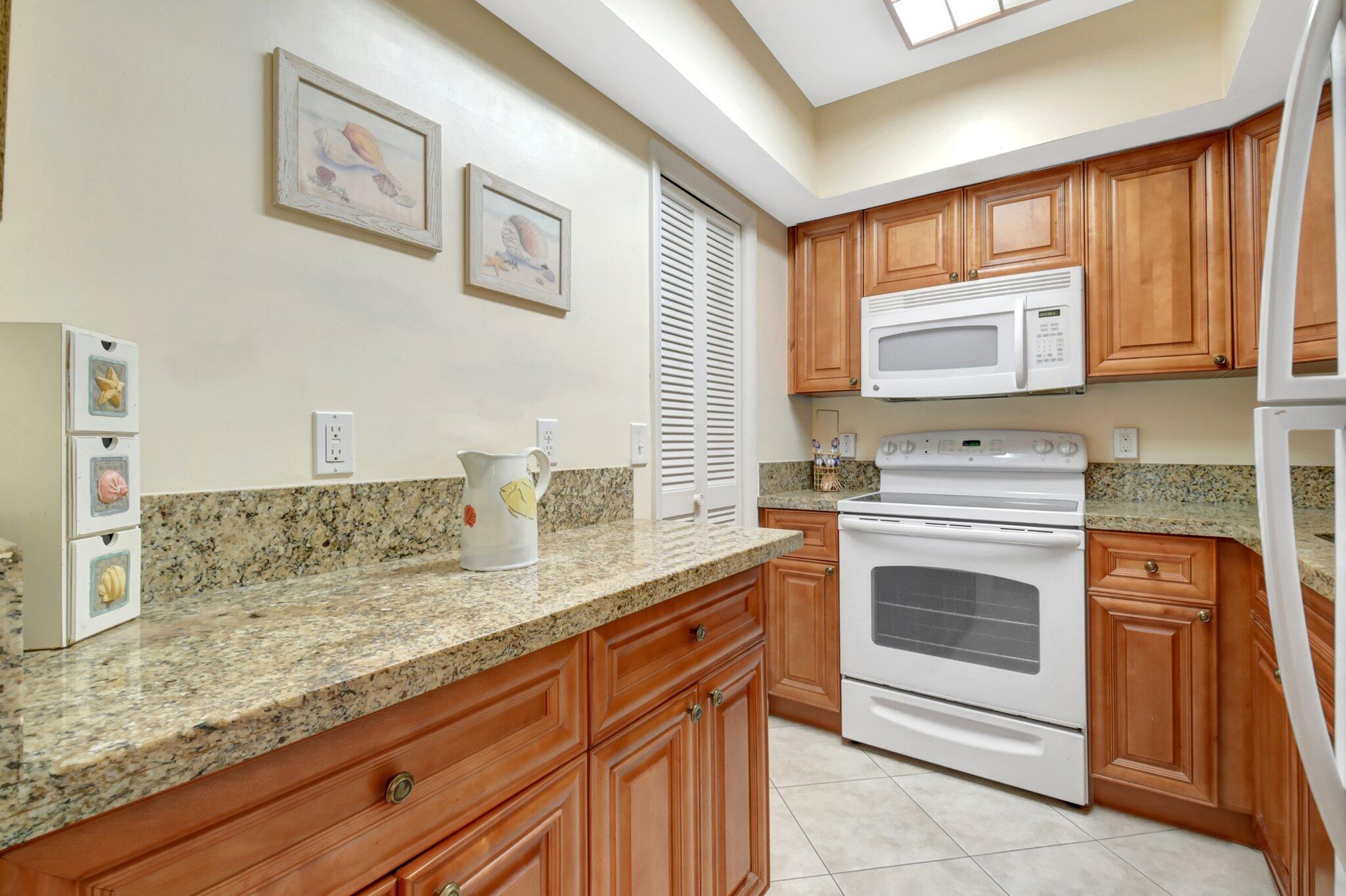 5505 North Ocean Boulevard, Unit 13105 Ocean Ridge, FL 33435 - Photo 16 of 40 a kitchen with granite countertop stainless steel appliances stove microwave and sink