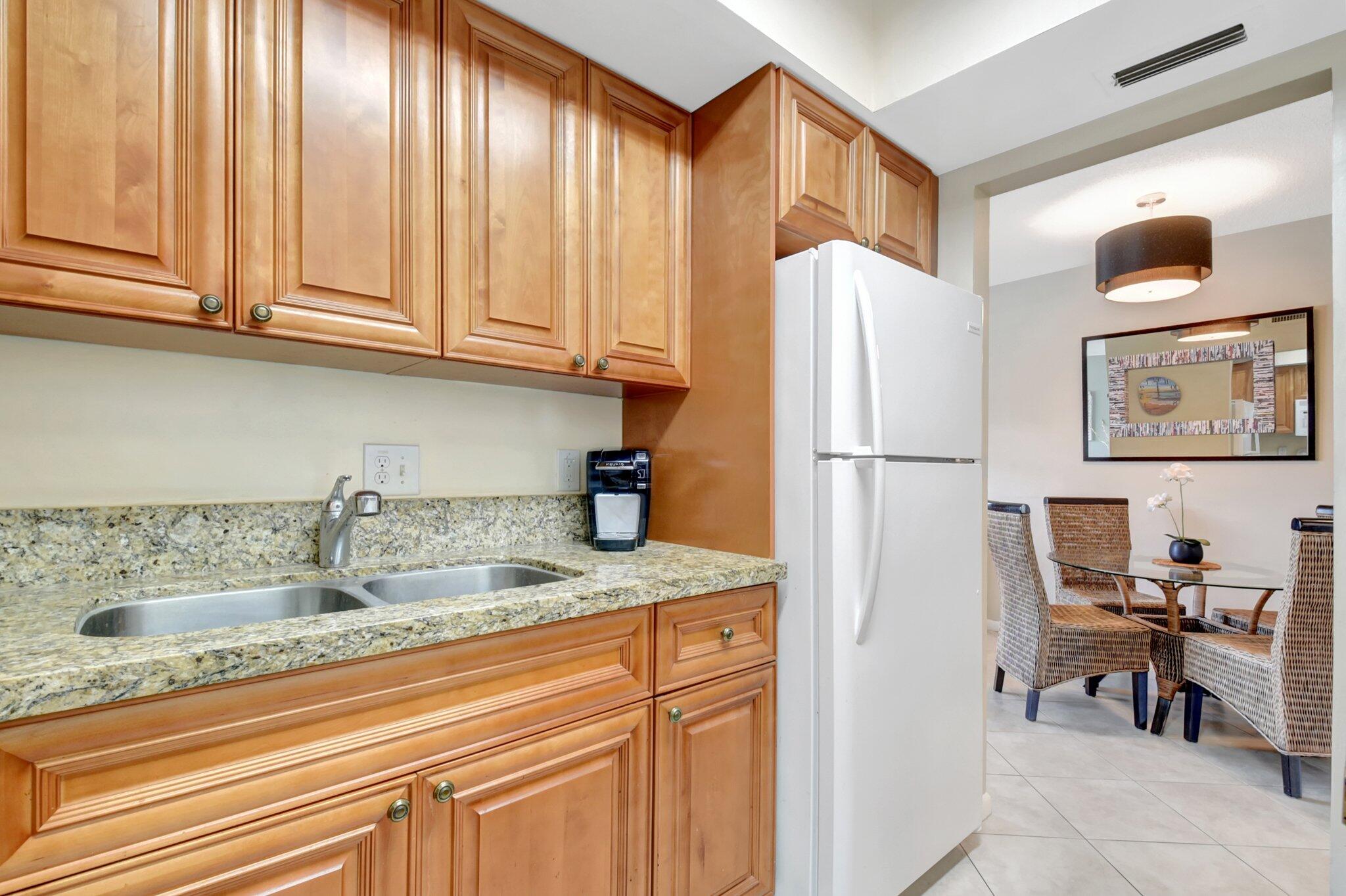 5505 North Ocean Boulevard, Unit 13105 Ocean Ridge, FL 33435 - Photo 18 of 40 a kitchen with stainless steel appliances granite countertop a refrigerator sink and cabinets