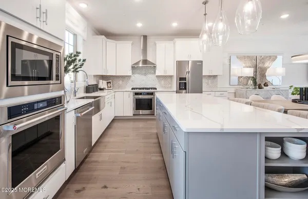 a large kitchen with stainless steel appliances kitchen island granite countertop a stove a sink and a microwave