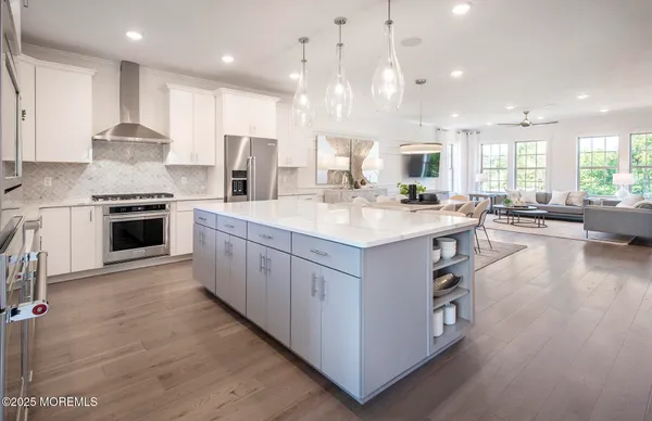 a large kitchen with stainless steel appliances lots of white cabinets and wooden floor