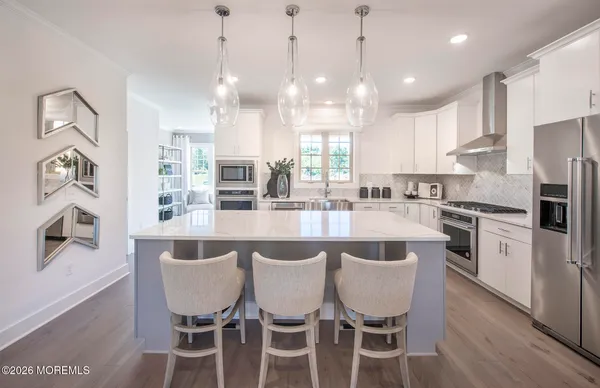 a large kitchen with a dining table chairs stainless steel appliances and cabinets