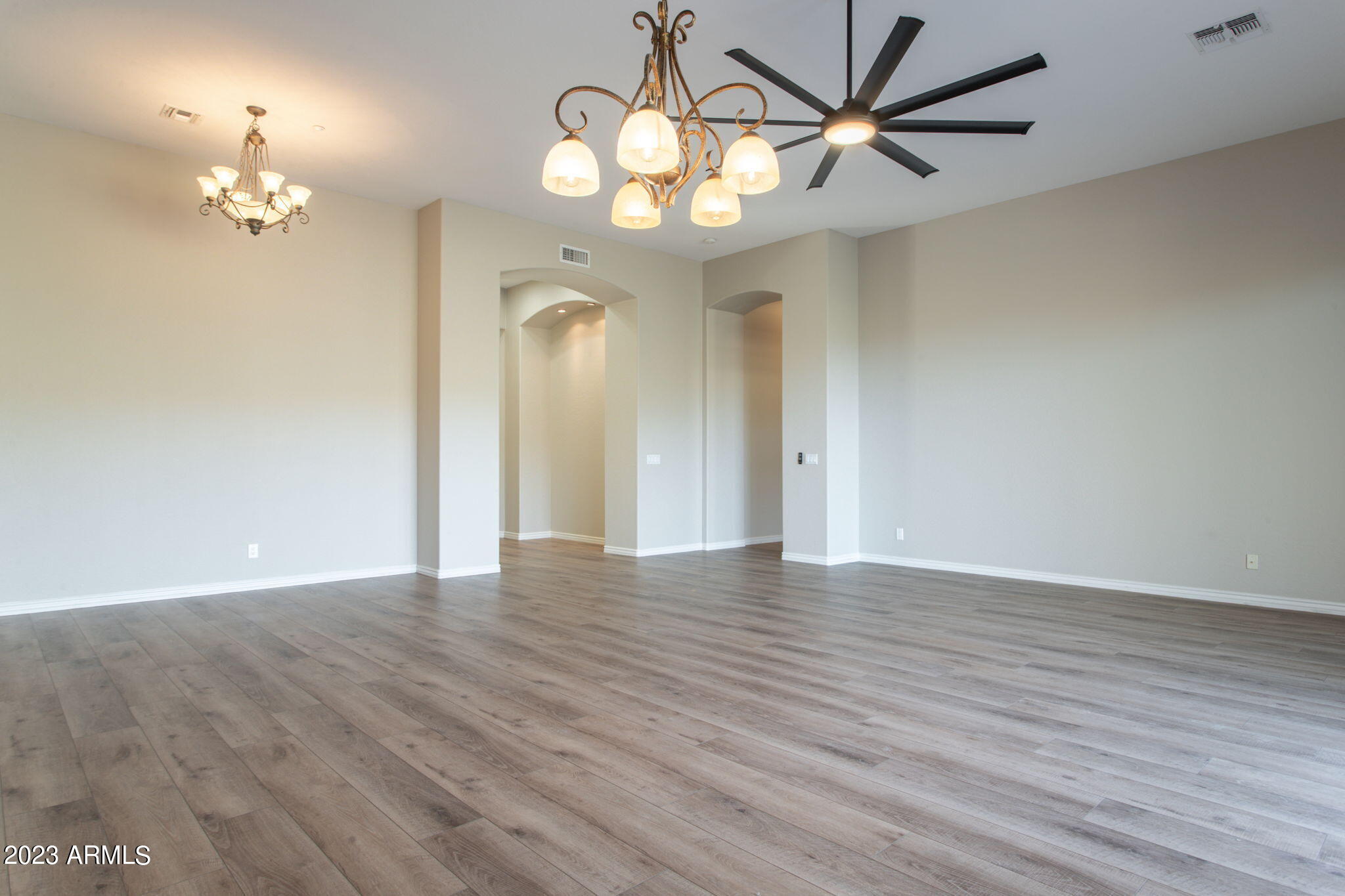 42409 North Back Creek Way Anthem, AZ 85086 - Photo 23 of 87 a view of an empty room with a chandelier fan and wooden floor