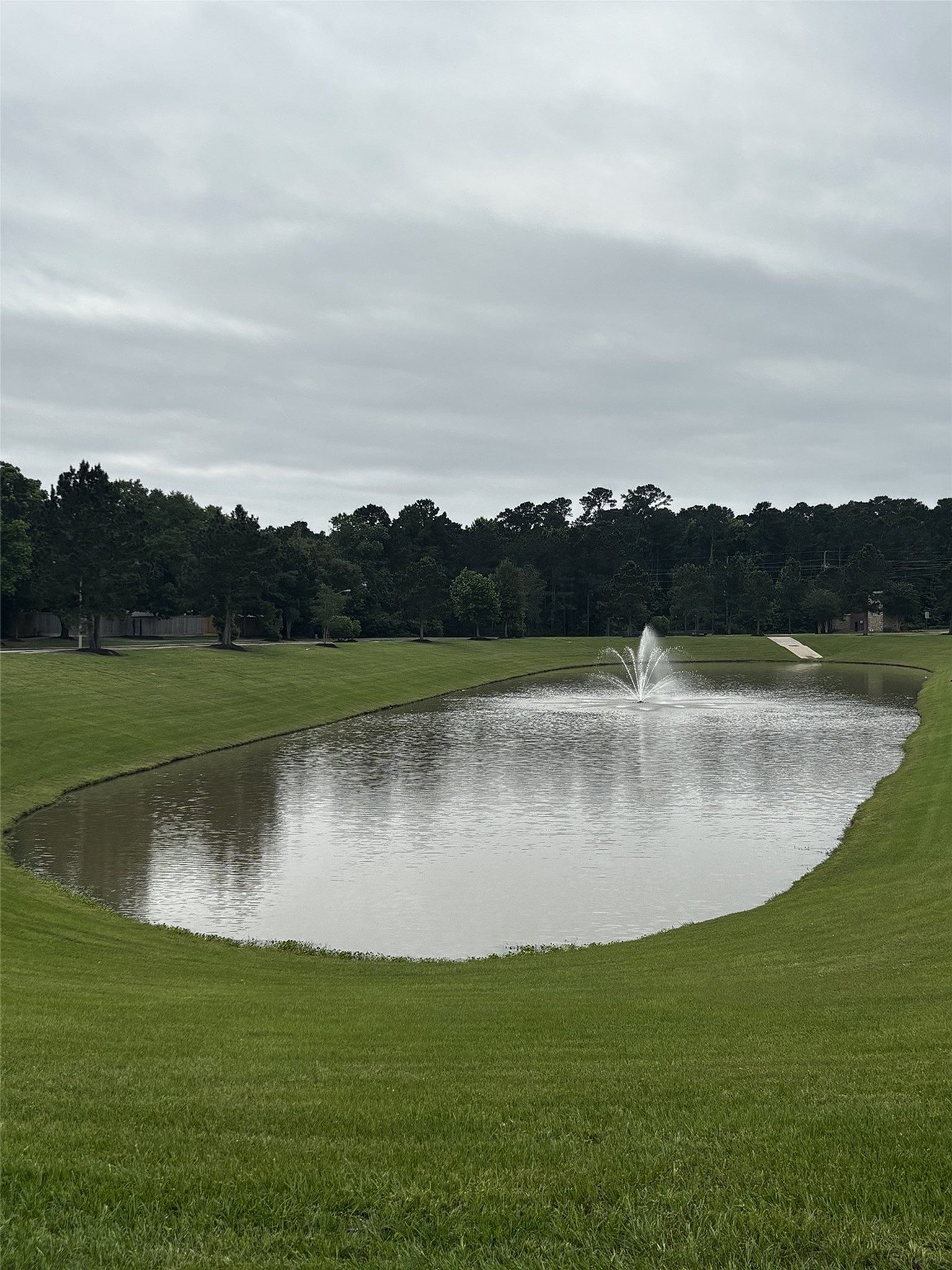 7562 Fettle Lane Conroe, TX 77304 - Photo 29 of 30 Scenic community pond with fountain, picnic tables, peaceful water views, and open green space perfect for relaxing outdoors.