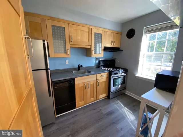 a kitchen with stainless steel appliances a refrigerator sink and wooden floor